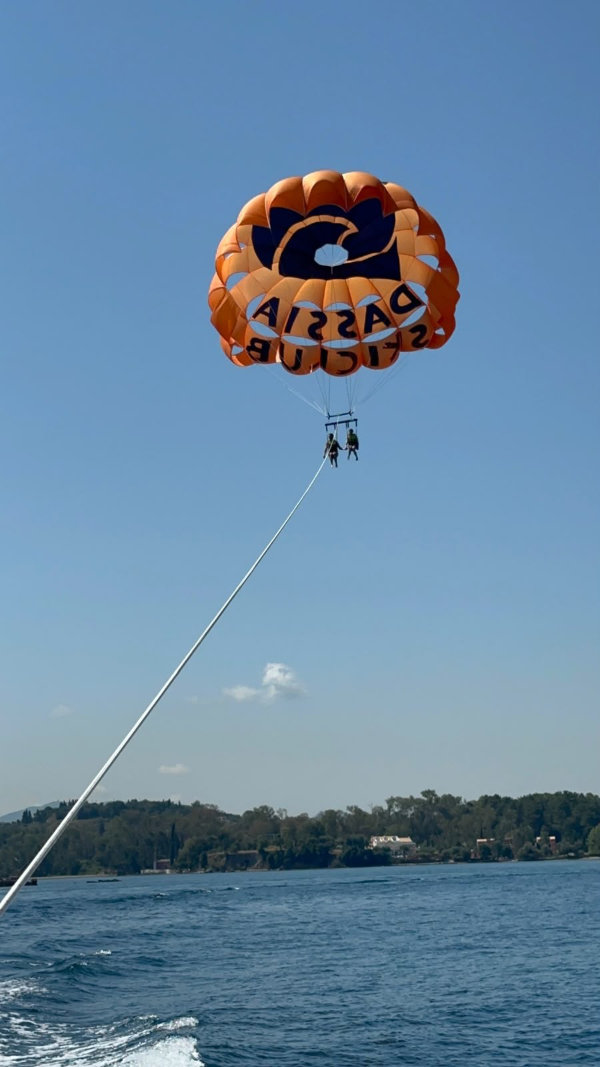 Gavin and Mini McGavin high in the air, dangling beneath a parachute
